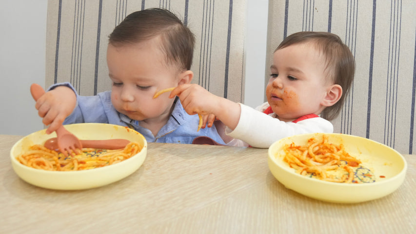 two babies eating pasta on ladydaidy plates